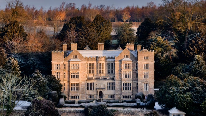 Fountains Hall is seen from a snowy bank in the winter
